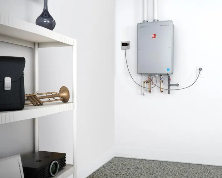 A water heater mounted on the wall next to a white shelving unit with a projector and a brass instrument on its shelves.