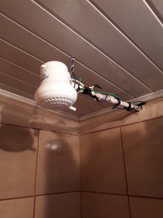 An improperly installed bathroom exhaust fan with exposed wiring near the water heater.